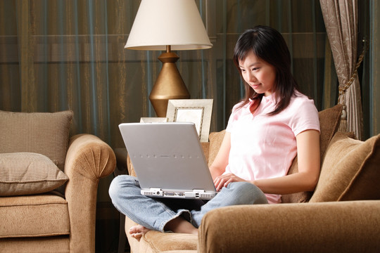 坐在沙发上用笔记本电脑的女人