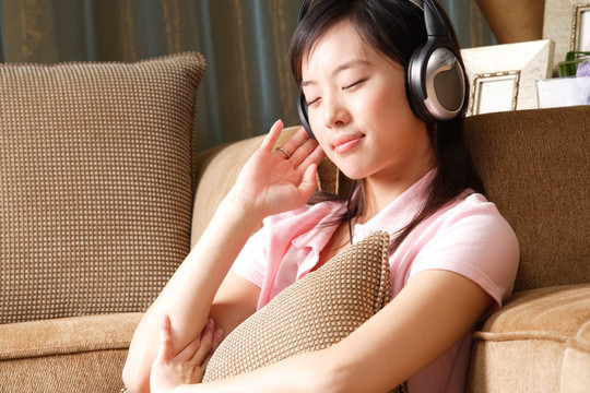 坐在沙发上戴着耳机听音乐的女人