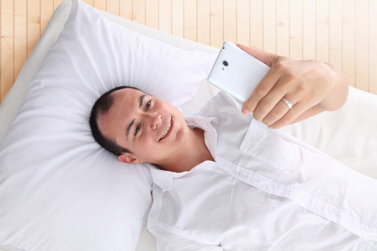 躺在床上使用手机的男人