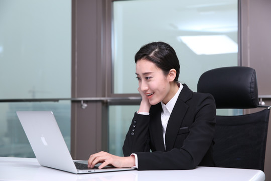 在办公室用笔记本电脑的微笑女人