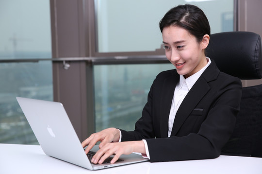 微笑的女经理在用笔记本电脑