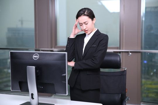 疲劳的女商务人士站在办公室里