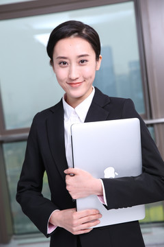 抱着笔记本电脑微笑着的女人
