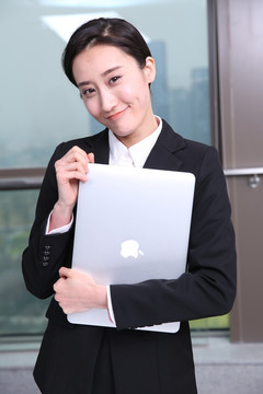 抱着笔记本电脑微笑着的商务女士