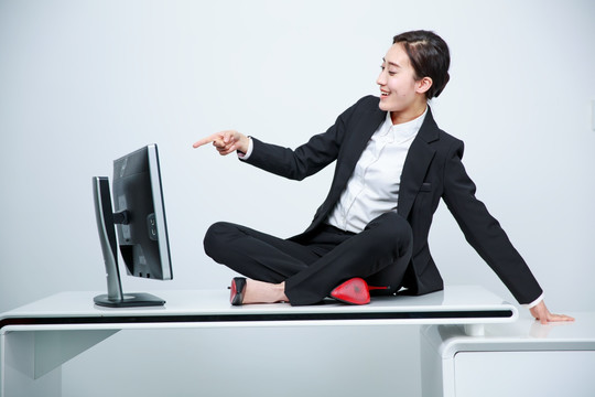 盘腿坐着指着电脑的商务女士