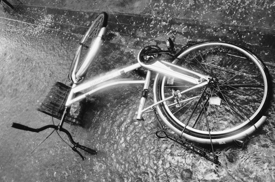 倒在暴雨里的自行车