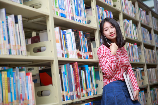 在大学图书馆里戴着耳机看着右边的女学生