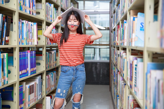 女学生在图书馆里拿书盖着头