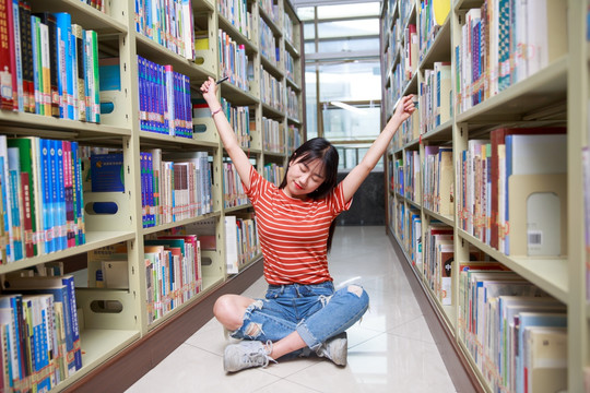 坐在图书馆地上伸懒腰的女大学生