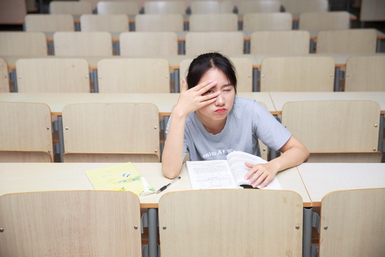 眨着眼睛的女学生坐在大学教室里