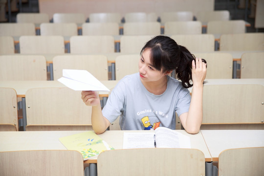 嘟着嘴看着手上的纸飞机的女大学生