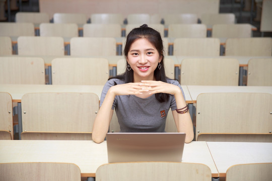 微笑的女学生坐在大学教室里