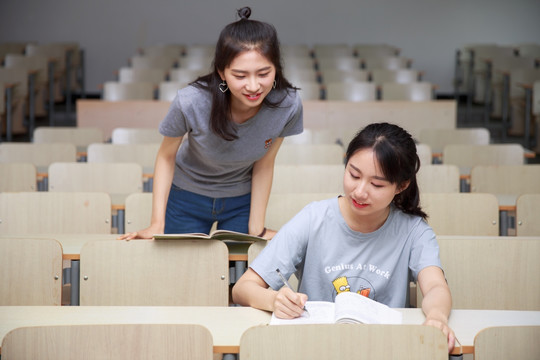 在大学教室里帮助同学解答问题的女学生