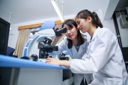 两名大学生在用显微镜观察标本