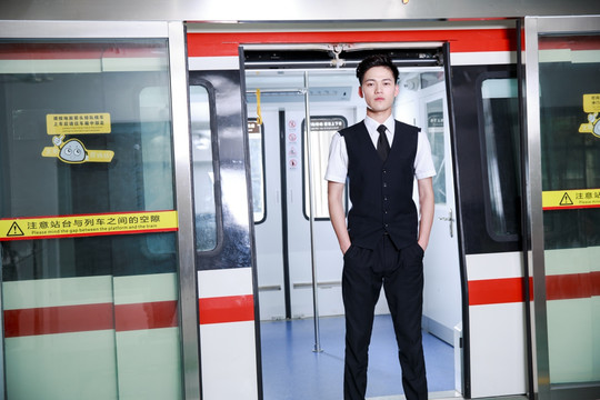 双手插裤袋站在地铁门口的男乘务员