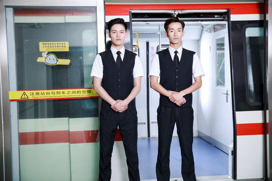 站在地铁门口的两名男乘务员
