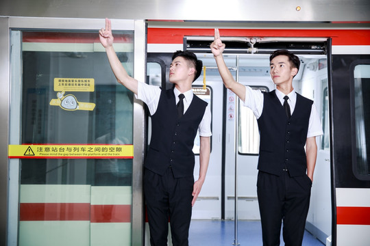 竖起手指站在地铁门口的两名乘务员