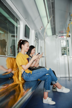 乘坐地铁微笑着玩着手机的女人
