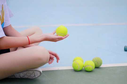 坐在地上拿着一个网球的女大学生