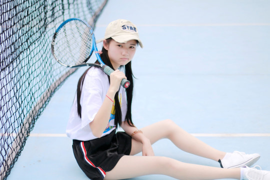 坐在地上拿着网球拍的女大学生