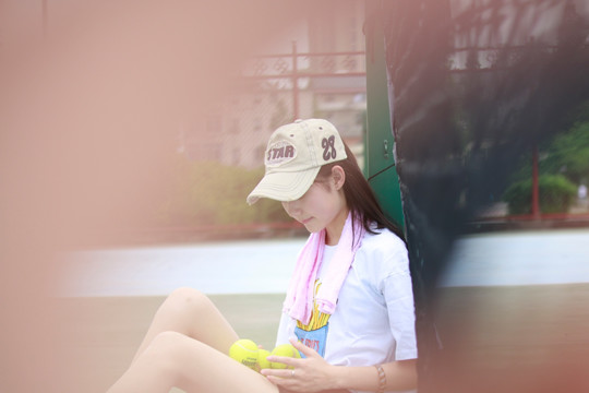 坐在地上看着网球的女大学生