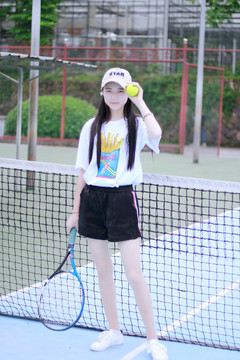 女大学生拿着网球拍和网球