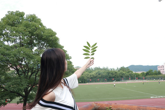 在校园里看着树叶的女大学生