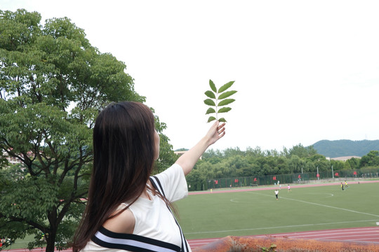 在校园里拿着树枝的女学生