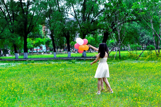 绿草地手拿气球的青春女孩