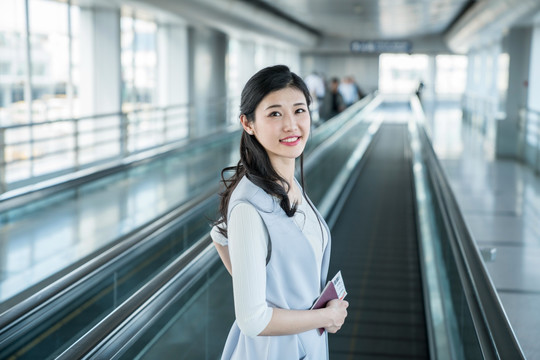 年轻商务女士在机场乘坐移动电梯