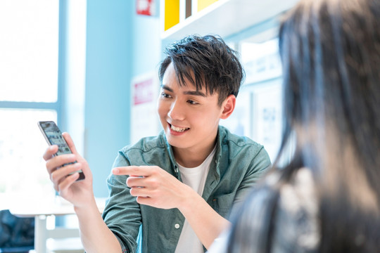 年轻男子向朋友展示手机