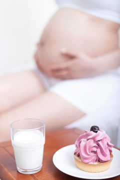孕妇面前摆放着蛋糕和牛奶