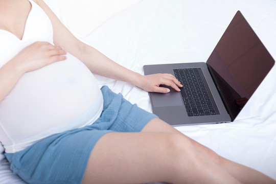 孕妇坐在床上使用笔记本电脑