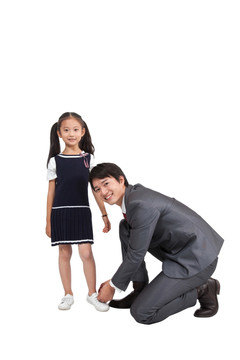 棚拍商务装年轻父亲为穿裙子的小女孩系鞋带