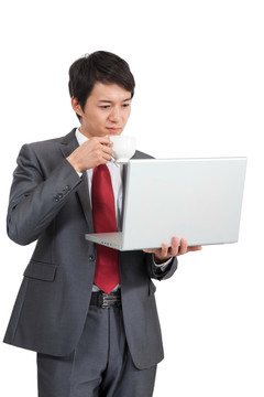 棚拍商务装年轻男人喝咖啡使用笔记本电脑