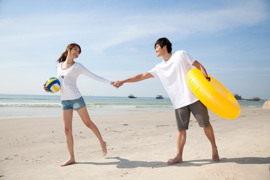 年轻情侣在海边度假玩沙滩排球