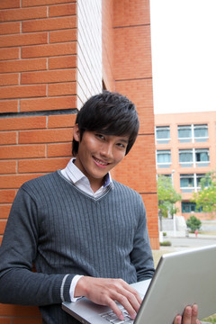 年轻男大学生在校园里使用笔记本电脑
