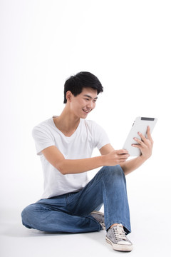 棚拍休闲装年轻男人盘腿坐玩平板电脑