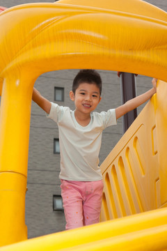 小男孩在幼儿园内玩滑梯