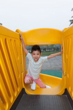 小男孩在幼儿园内玩滑梯