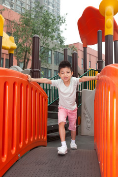 小男孩在幼儿园内玩滑梯