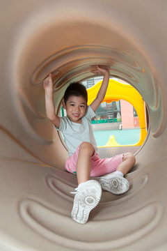 小男孩在幼儿园内玩滑梯