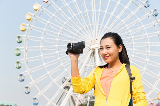 年轻女人手拿DV在游乐园