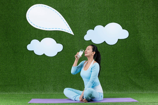 草地创意青年女性坐在瑜伽垫上喝牛奶