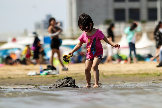 在海边玩沙子的小女孩