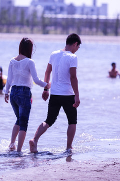 站在海滩上游玩的情侣