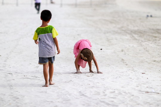 站在沙滩上玩沙子的女孩
