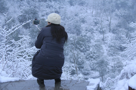 雪景中拿自拍杆自拍的女人