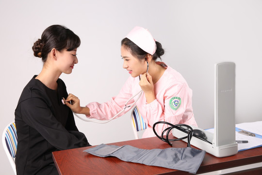 漂亮护士使用听诊器为病人检查