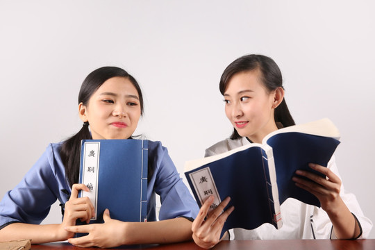 年轻女学生给同学看书上的内容